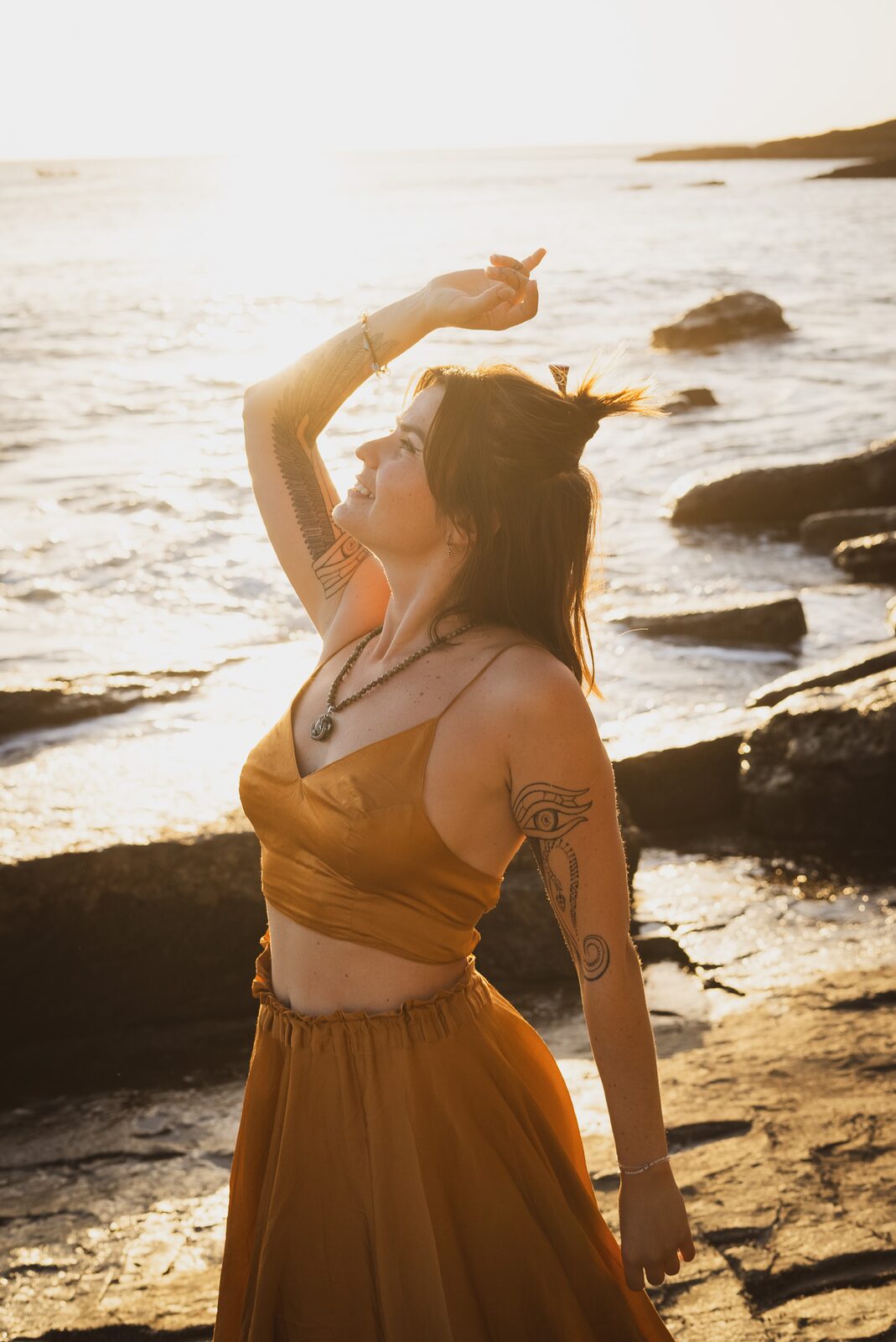 TSA Revna radiant in golden-hour coastal light, embodying joy and freedom in full alignment with herself